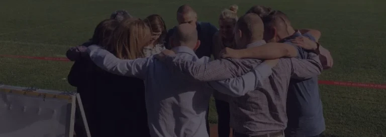Corporate team in a group huddle, expressing unity and motivation outdoors.