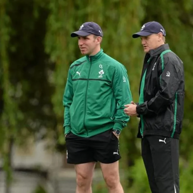 Two sports leadership coaches discuss strategies in a serene outdoor setting.