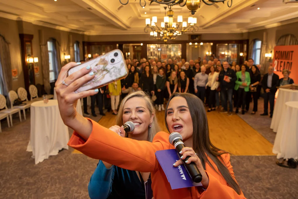 McNulty event attendees in selfie with presenters, encapsulating 'Commit 2 Lead' enthusiasm.