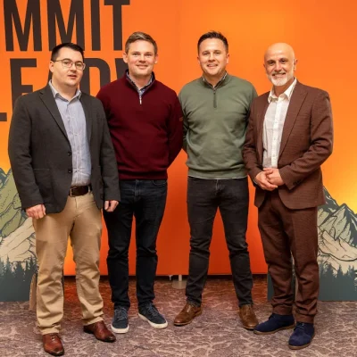 Group of four professionals posing at Commit 2 Lead event with a motivational backdrop.