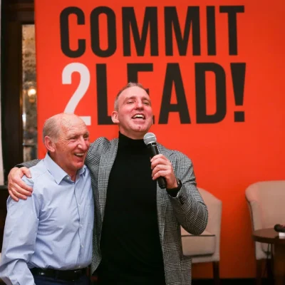 Joyful interaction between two attendees with a microphone at the Commit 2 Lead event.