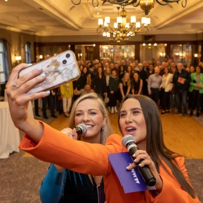 Two presenters taking a selfie with the audience at the Commit 2 Lead event.