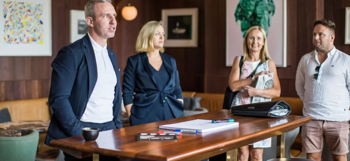 Senior executive discussing strategies with attentive colleagues in a café setting.