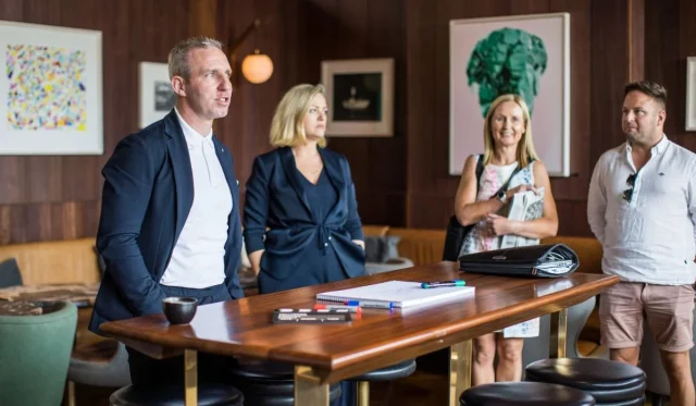Senior executive discussing strategies with attentive colleagues in a café setting.