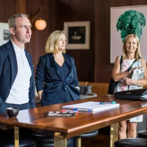 Senior executive discussing strategies with attentive colleagues in a café setting.