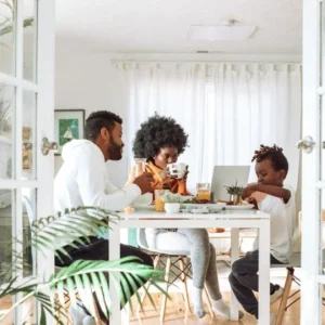 Family engaging in a meal together in a brightly-lit, plant-filled modern dining room, reflecting a harmonious work-life balance.
