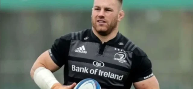 Rugby player Sean O'Brien holding a rugby ball, wearing a black Bank of Ireland jersey during a practice session.