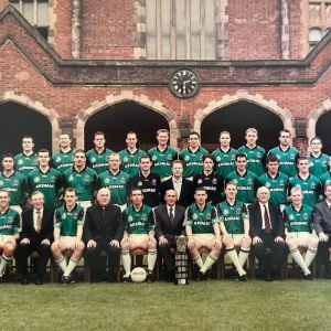 Group photo of the Queen's University Gaelic Football team standing in front of a historic building, showcasing players and coaching staff.