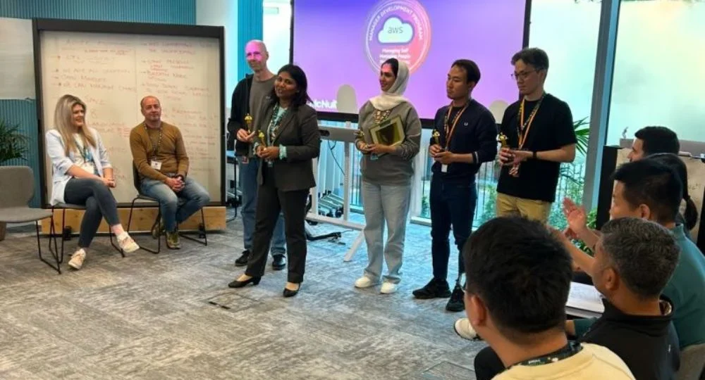 Group of AWS APAC leaders and McNulty Performance team during a leadership development session, with participants engaged and receiving awards in a workshop setting.